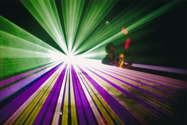 Das Bild zeigt eine lebendige Messeszene mit vielen Besuchern, die sich an verschiedenen Ständen und Displays versammeln. Große Werbebanner mit Aufschriften wie „Lightpower“ und „The world has changed“ heben das Thema Licht- und Veranstaltungstechnik hervor. Im Hintergrund sind auffällige Dekorationen wie beleuchtete Kugeln und große Lautsprecher-Attrappen zu sehen, während vorne mehrere Monitore und technische Geräte die Aufmerksamkeit auf sich ziehen. Die bunte Beleuchtung und die dichten Menschenmengen vermitteln eine dynamische und innovative Atmosphäre, typisch für eine Fachmesse dieser Art.