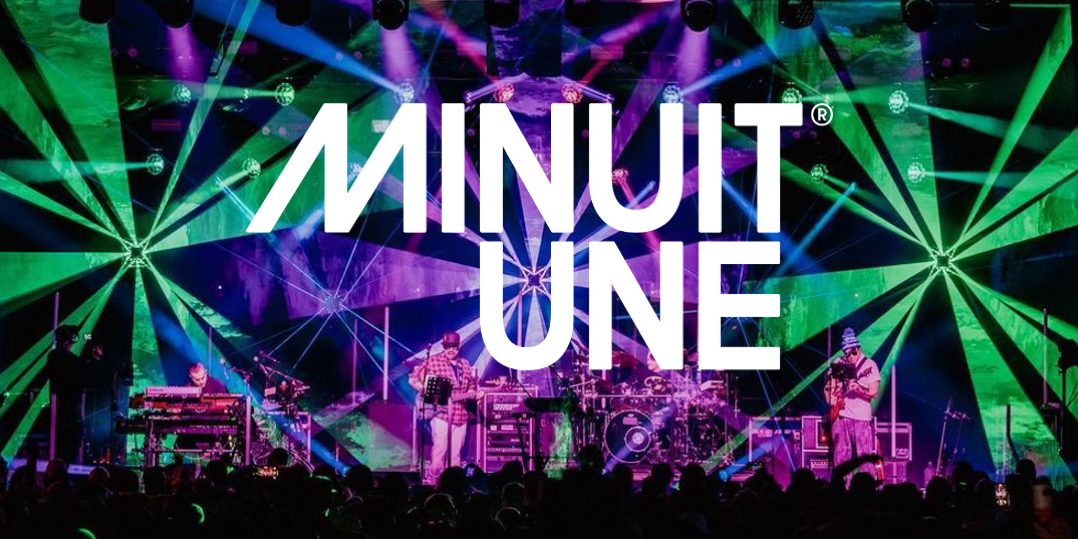 Banniere Minuit Une Das Bild zeigt eine beeindruckende Live-Bühnenszene mit einer dynamischen Lichtshow. Der Hintergrund ist von intensiven grünen und violetten Lichteffekten geprägt, die strahlenförmig von verschiedenen Punkten ausgehen und den gesamten Raum einhüllen. In der Mitte des Bildes befindet sich das große, weiße Logo von Minuit Une, das prominent über die Szene gelegt wurde. Auf der Bühne stehen mehrere Musiker, die von einer aufwendigen Lichtinstallation umgeben sind. Die Beleuchtung erzeugt eine immersive Atmosphäre, die typisch für die IVL-Technologie von Minuit Une ist. Die Kombination aus multidirektionalen Lichtstrahlen, Projektionen und der energiegeladenen Live-Performance vermittelt den Eindruck eines intensiven, mitreißenden Konzerterlebnisses.