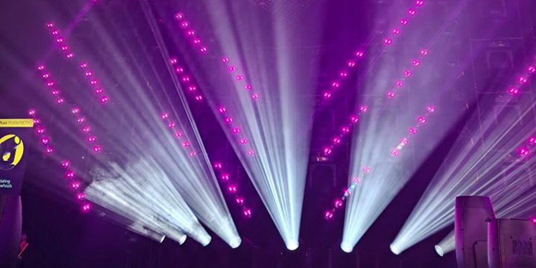 Violet and white beams of light create a stage filled with dynamic effects.