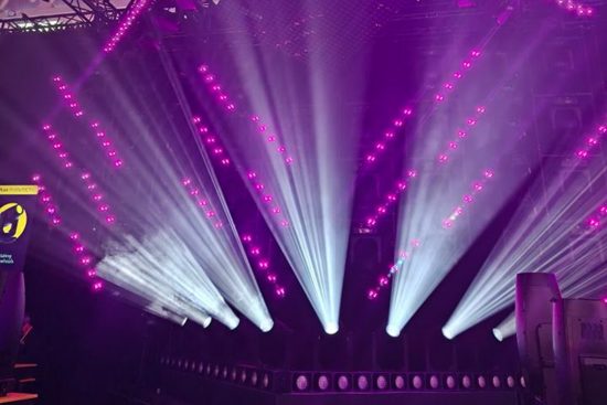 Violet and white beams of light create a stage filled with dynamic effects.