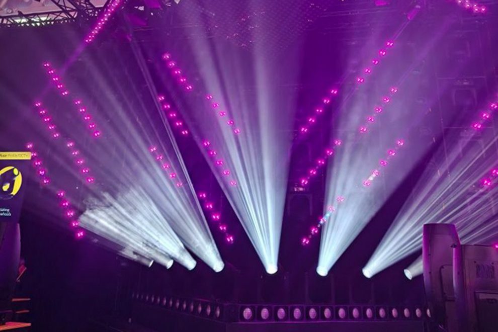 Violet and white beams of light create a stage filled with dynamic effects.