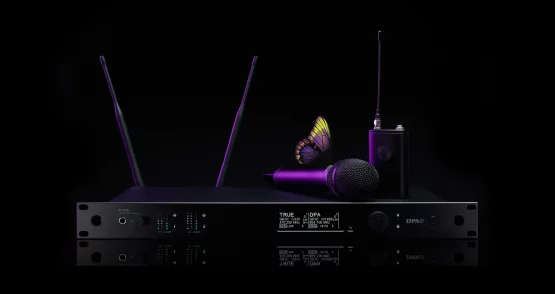 Das Bild zeigt ein hochwertiges Drahtlossystem aus der DPA N-Serie Digital Wireless, bestehend aus mehreren Komponenten. Im Mittelpunkt steht ein N-DR1 Digital Wireless Receiver, ein professioneller Zweikanalempfänger mit zwei aufrecht stehenden Antennen, mehreren LED-Anzeigen und einem Display, das technische Informationen wie Frequenzen und Signalstärke darstellt.

Auf dem Empfänger liegt ein kabelloses Handmikrofon, das zum DPA d:facto™-Sortiment gehören könnte. Rechts daneben steht ein Bodypack-Transmitter mit einer angeschlossenen Antenne, der eine kompakte und robuste Bauweise aufweist. Das gesamte Equipment ist in einem eleganten, schwarzen Design mit modernen, lila Akzenten gehalten.

Besonders auffällig ist ein Schmetterling, der auf dem Mikrofon platziert ist. Dies könnte symbolisch für die klare und natürliche Klangqualität der DPA-Produkte stehen. Der Hintergrund ist tiefschwarz, was das Equipment in den Fokus rückt und die hochwertige Ästhetik der Produktreihe unterstreicht.