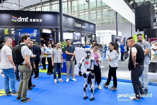 A robot is observed by trade visitors at the Prolight + Sound Guangzhou exhibition stand.