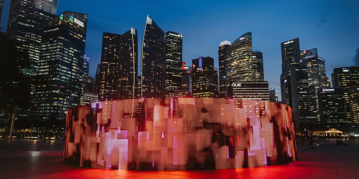Leuchtende Lichtinstallation vor der nächtlichen Skyline von Singapur