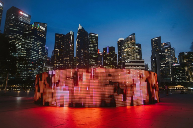 Leuchtende Lichtinstallation vor der nächtlichen Skyline von Singapur