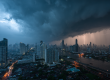 Bangkok skyline under dark storm clouds, heavy rain falls over the city and the river.