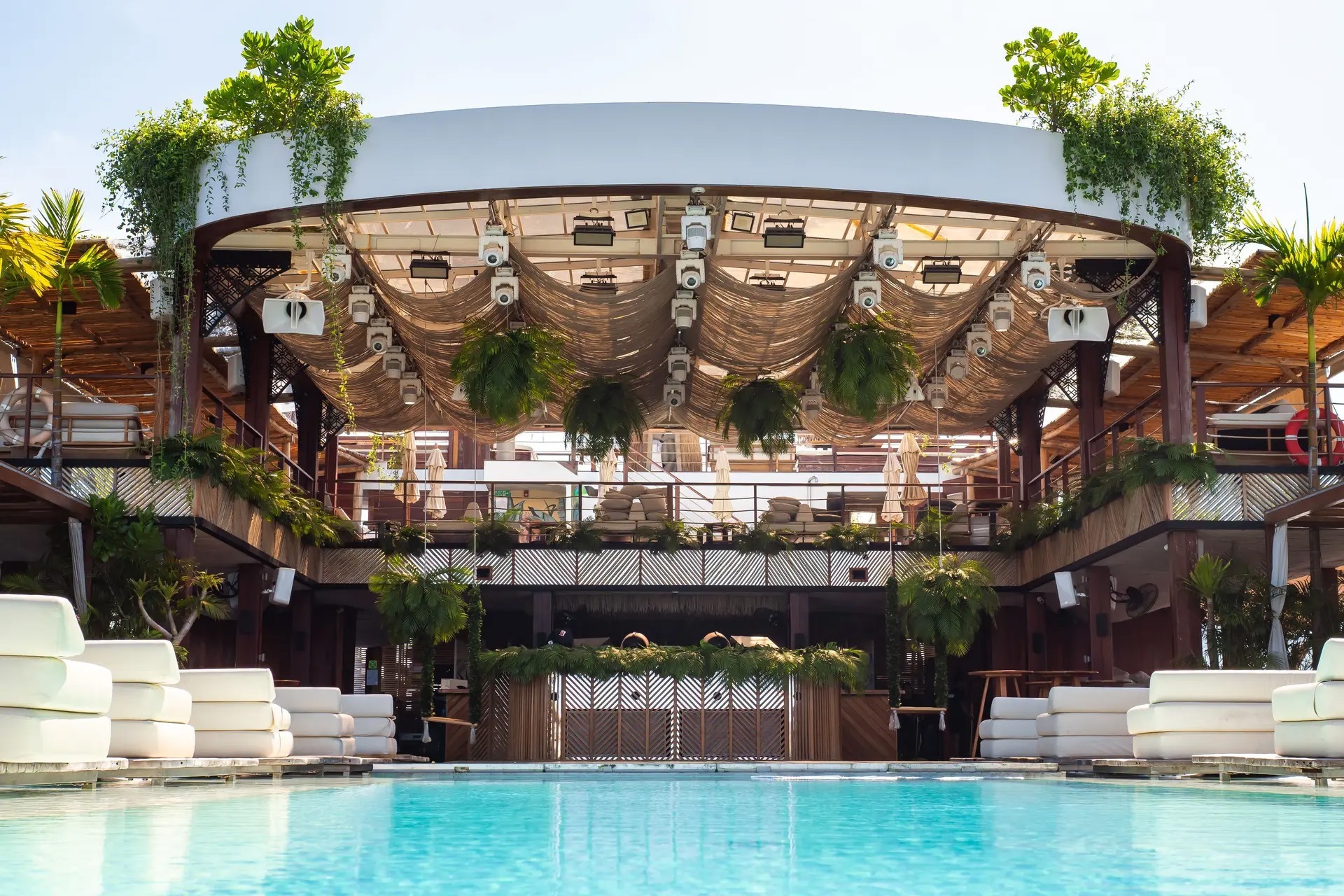 Tropical beach club with pool, palm trees and integrated white loudspeakers