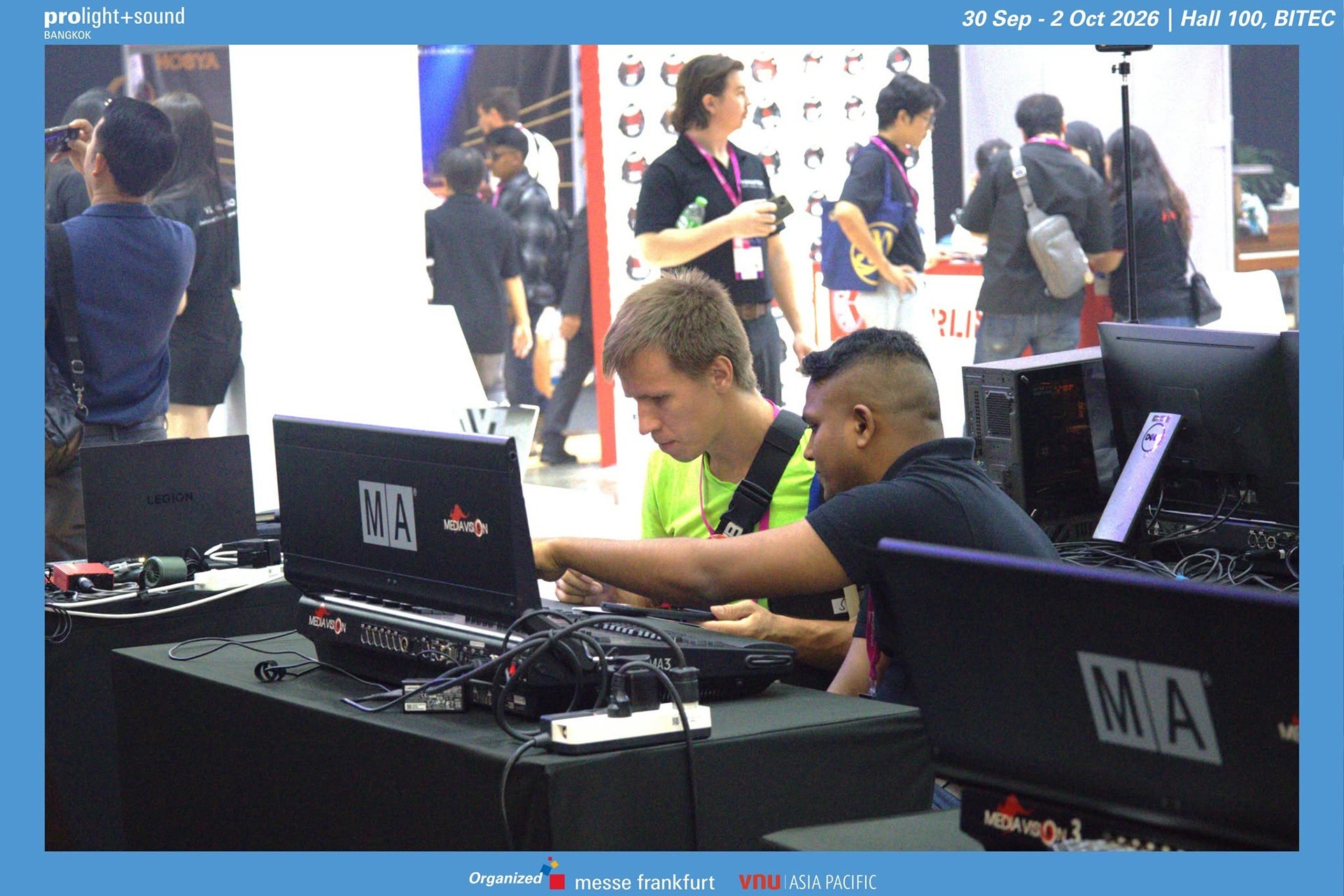 Two trade visitors test lighting control software together at an exhibition stand.