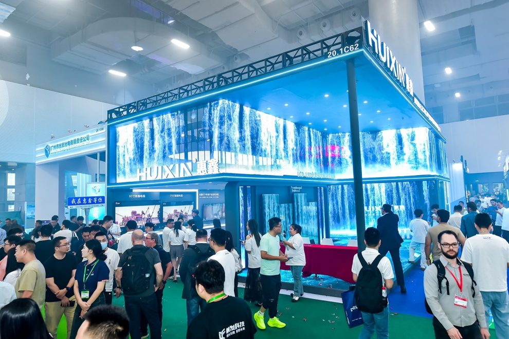 Exhibition stand with large LED installation, many visitors talking and exploring