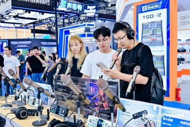 Besucher testen Mikrofone und Kopfhörer an einem Audiostand