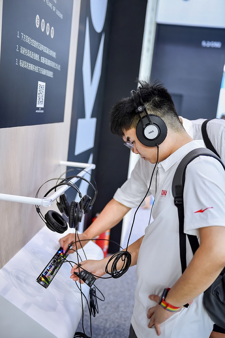 A visitor testing headphones and an audio interface at an exhibition stand