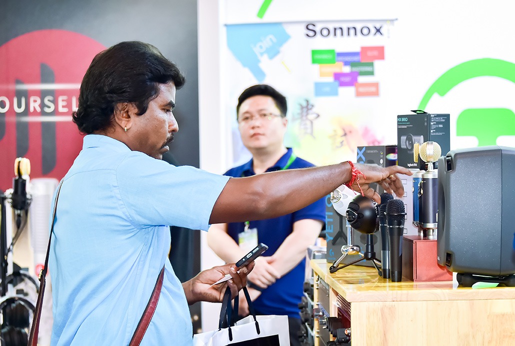 Visitor testing microphones at a stand, with loudspeakers and audio equipment nearby
