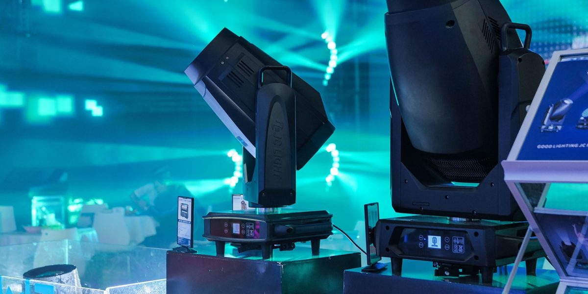Professionelle Moving Lights erzeugen türkisfarbene Lichtstrahlen in einer Veranstaltungshalle.