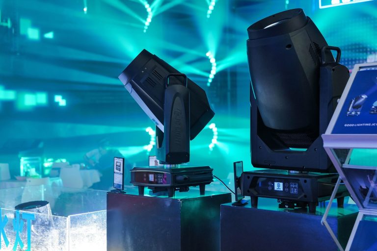 Professionelle Moving Lights erzeugen türkisfarbene Lichtstrahlen in einer Veranstaltungshalle.